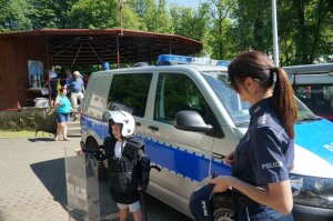 dziecko w policyjnym sprzęcie, radiowóz i policjantka