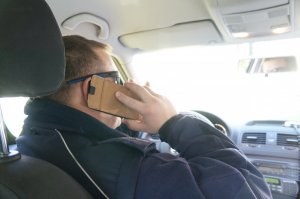 policjant rozmawia przez telefon w środku samochodu