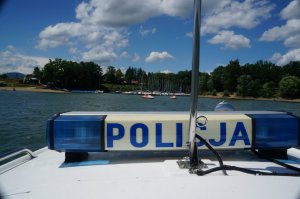 napis policja na policyjnej motorówce w tle brzeg jeziora