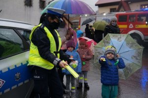 policjantka stoi wraz z dziećmi i pokazują odblaski