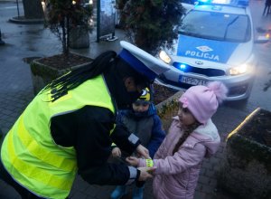policjantka wręcza odblaski dzieciom