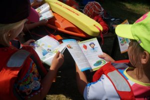 fragment dzieci trzymają rozłożone książeczki o bezpieczeństwie nad wodą