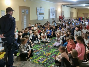 policjant stoi tyłem przed nim siedzą dzieci zdjęcie kolorowe zrobione w sali
