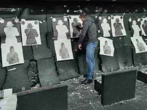 zdjęcie kolorowe zrobione na strzelnicy policjant zaznacza wyniki strzelania na tarczy